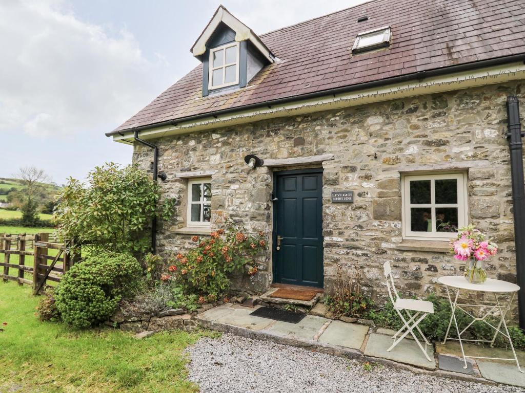 a stone cottage with a green door and a table at Red Kite Lodge in Llandeilo