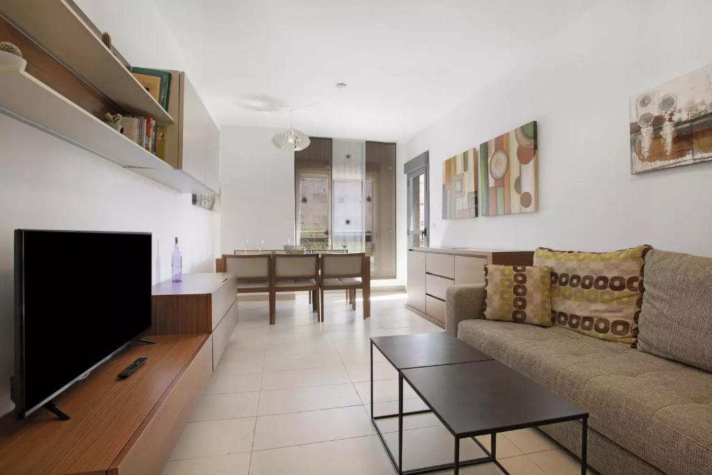 a living room with a couch and a flat screen tv at MALAGA CAMPUS APARTMENT Piscina y Parking incluido in Málaga