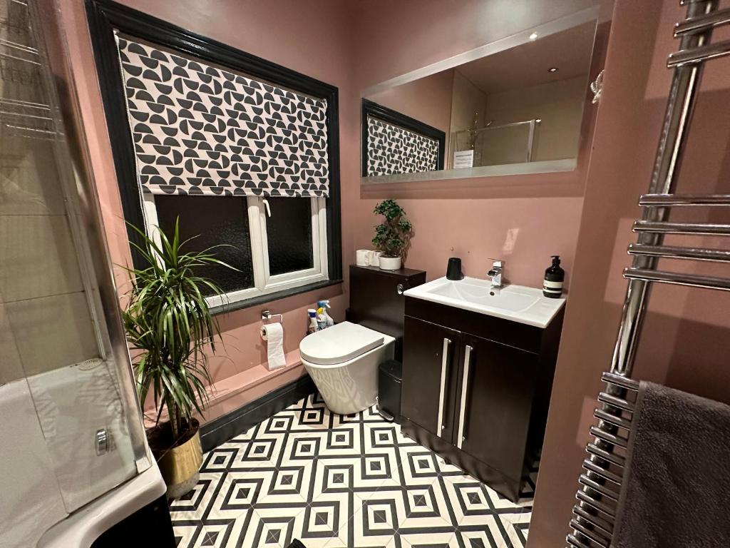 a bathroom with a sink and a toilet and a mirror at Suffolk pink house, Newmarket town centre in Newmarket