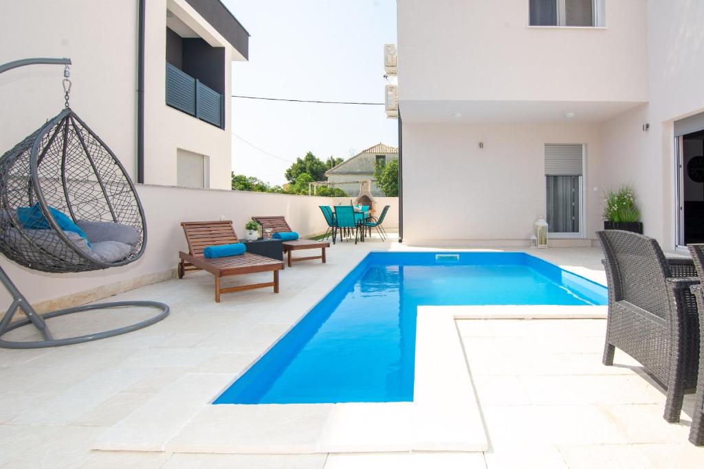 uma piscina num quintal com um baloiço e uma casa em Apartment Cosic em Vir