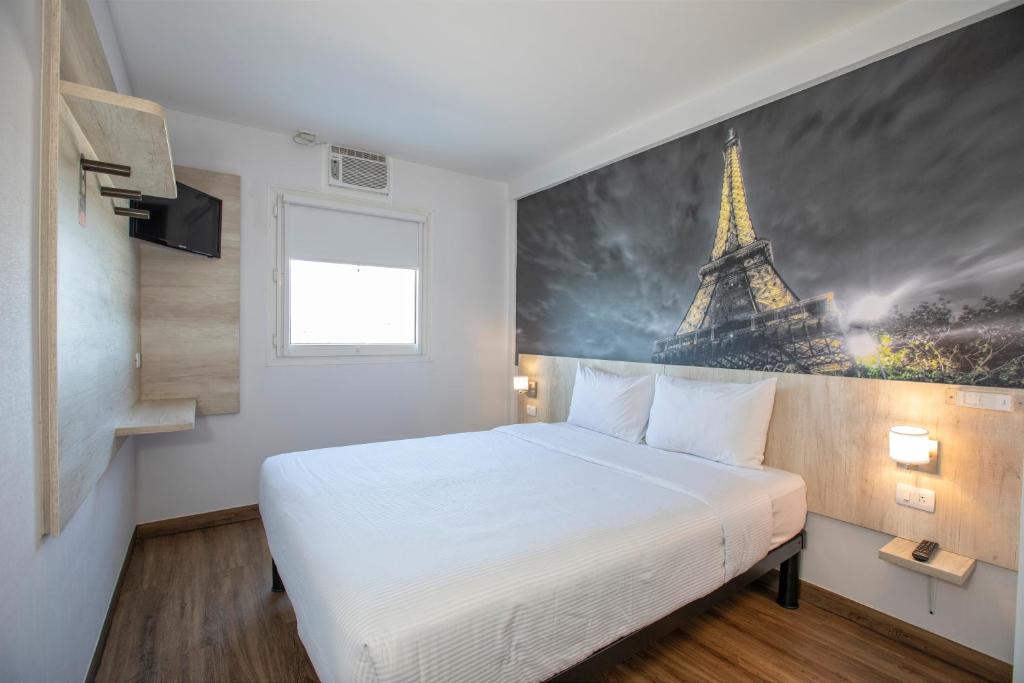 1 dormitorio con 1 cama con una foto de la torre Eiffel en Hotel Hi! Guadalupe, en Monterrey