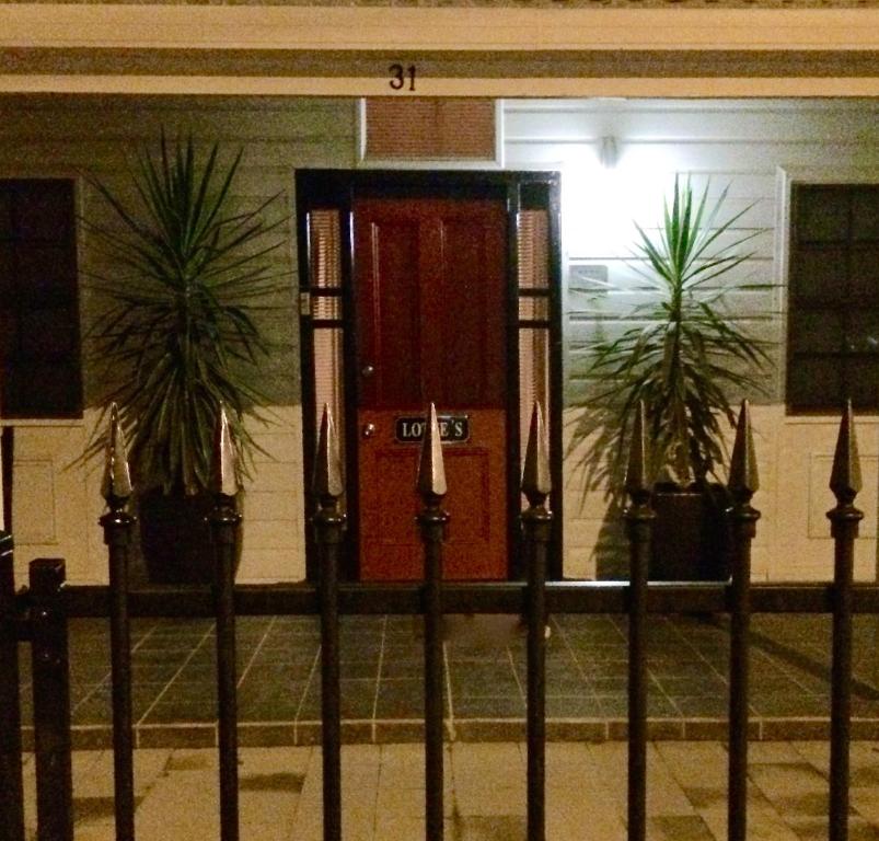 a front door of a building with two plants at Lotte's Cottage in Broken Hill
