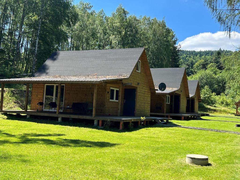 a log cabin with a porch in the grass at Domki Bieszczady - Baza uŚmiechów in Ustrzyki Dolne