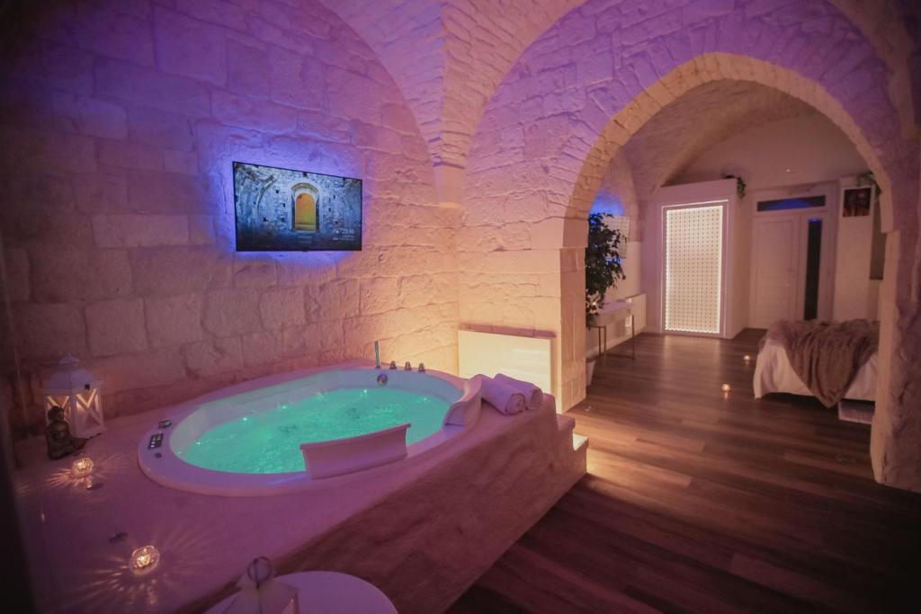 a large bathroom with a tub in a stone wall at Romantic Suite with Private Jacuzzi Malely Suite in Martina Franca
