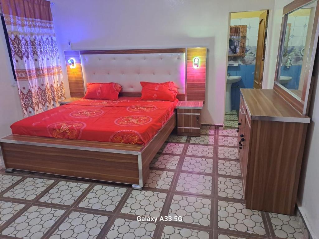 a bedroom with a bed with red pillows and a mirror at VILLE FRANCE PATOIS in Thiès