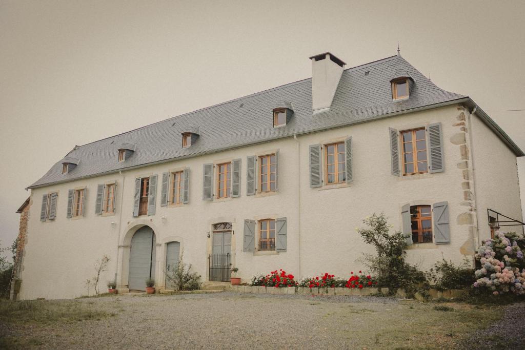 duży biały dom z czerwonymi kwiatami przed nim w obiekcie Domaine de Berducq w mieście Monein