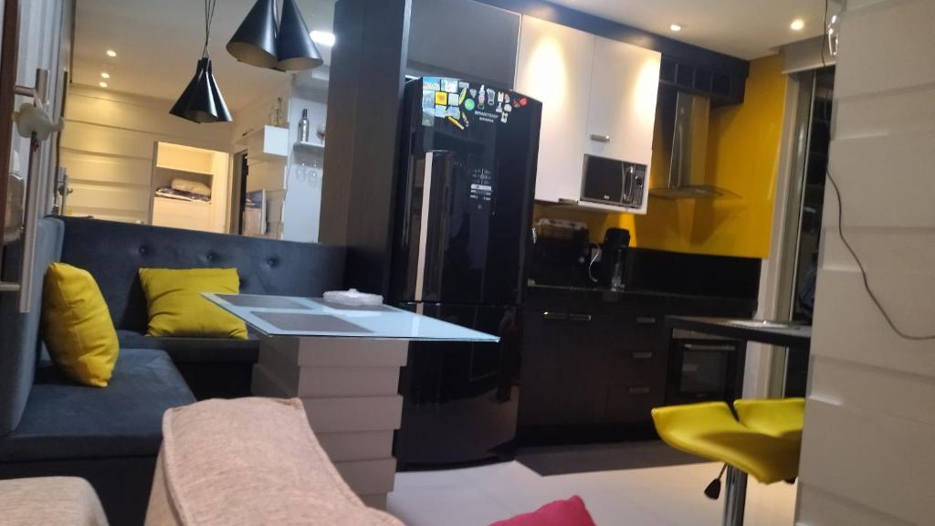 una pequeña cocina con mesa y almohadas amarillas en Studio em Guarulhos, perto do Aeroporto de Gru 15'min en Guarulhos