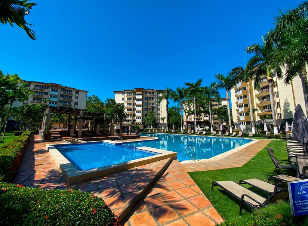 una piscina en un complejo con palmeras y edificios en Costa Linda walking distance to the beach, en Jacó