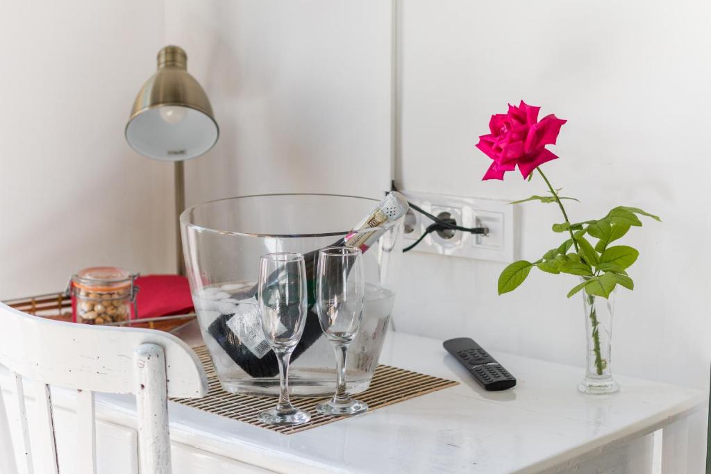 una mesa con dos copas de vino y un jarrón con una rosa en La Casa Vella EL BEDORC en Piera
