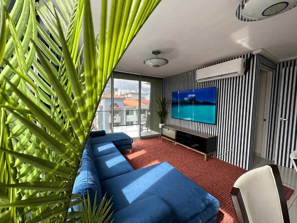 a living room with a blue couch and a tv at 7a in Panama City