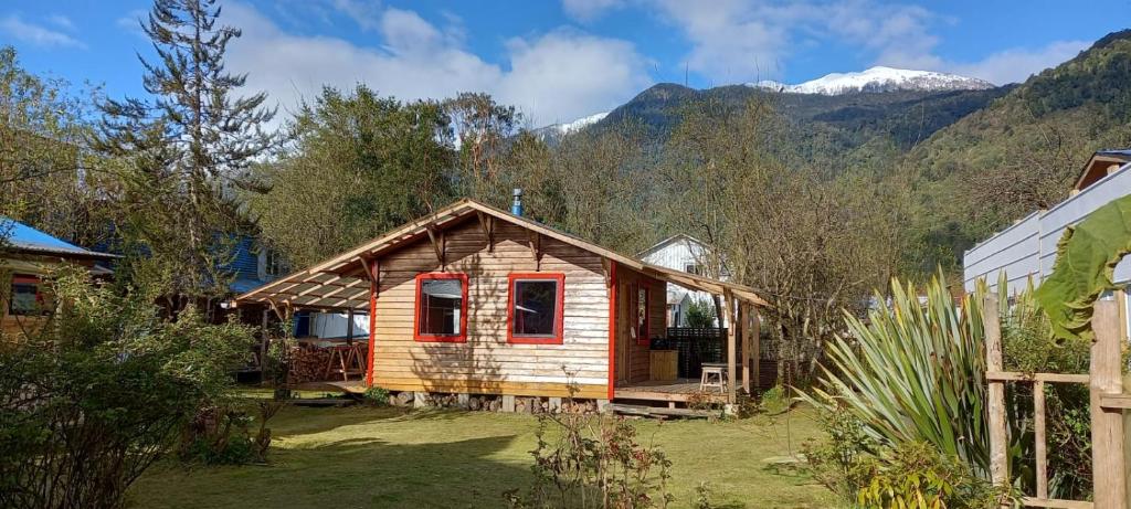 um pequeno chalé de madeira com montanhas ao fundo em Cabañas Turin em Puerto Puyuhuapi