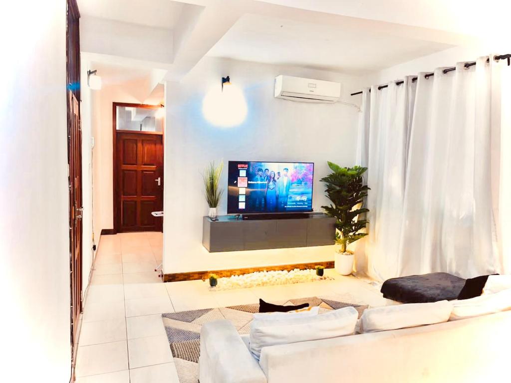 a living room with a couch and a tv at Luxurious apartment with King size bed in Dar es Salaam