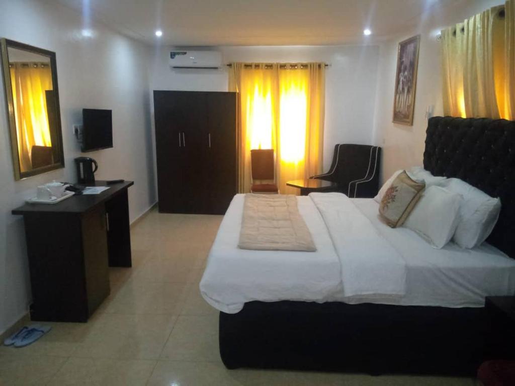 ein Hotelzimmer mit einem großen Bett und einem Schreibtisch in der Unterkunft Gregory University Guest House in Lagos