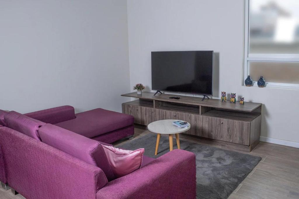 sala de estar con sofá púrpura y TV en Departamento Amoblado, en Lima