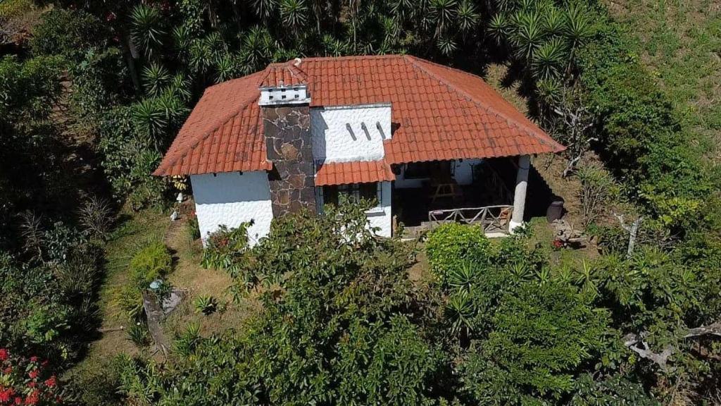 una piccola casa con un tetto arancione su una collina di Casa de campo amplia y tranquila a Juayúa