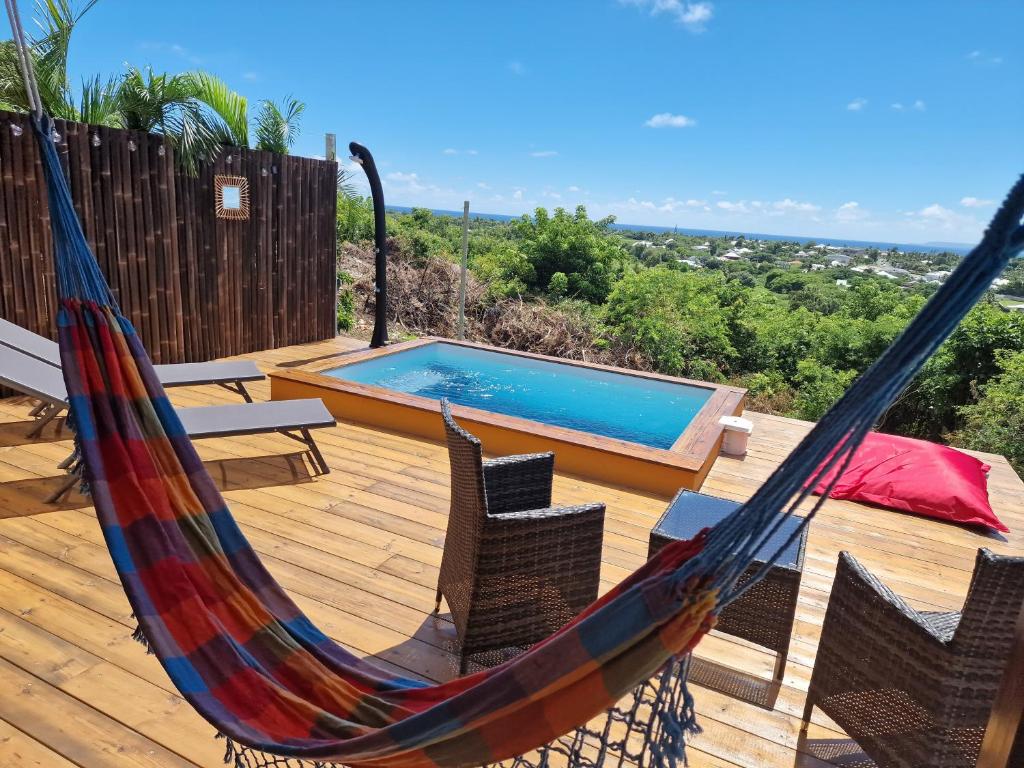 a hammock on a deck with a swimming pool at Le Jeïpur Villa vue mer piscine privée in Saint-François