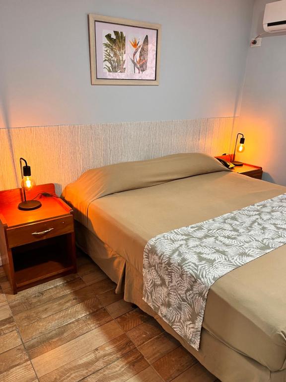 a hotel room with a bed and a nightstand with a bed sidx sidx sidx at ARASARÍ Hotel Iguazú in Puerto Iguazú