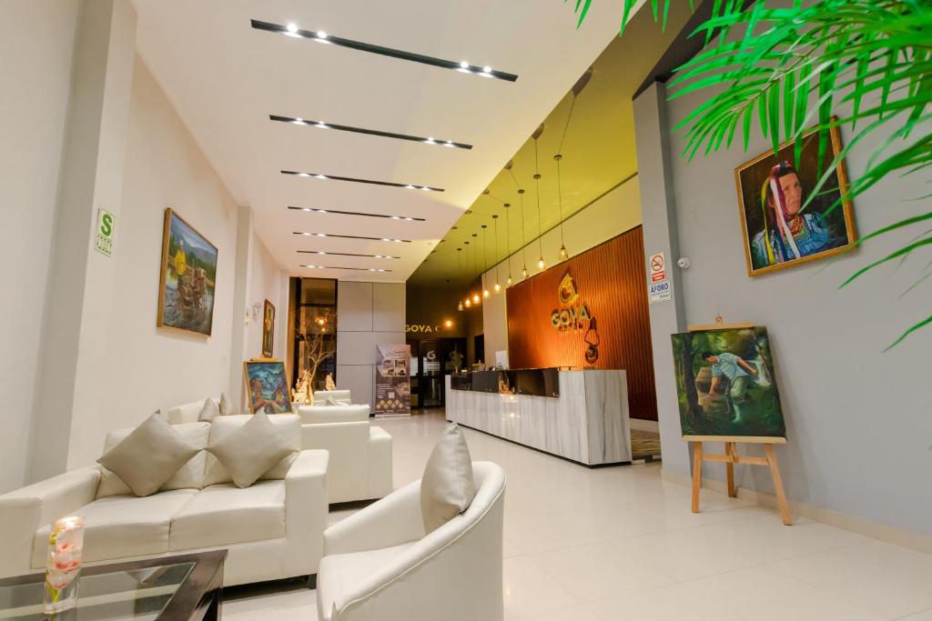 eine Lobby mit weißen Sofas und Gemälden an der Wand in der Unterkunft GOYA HOTEL in Jaén