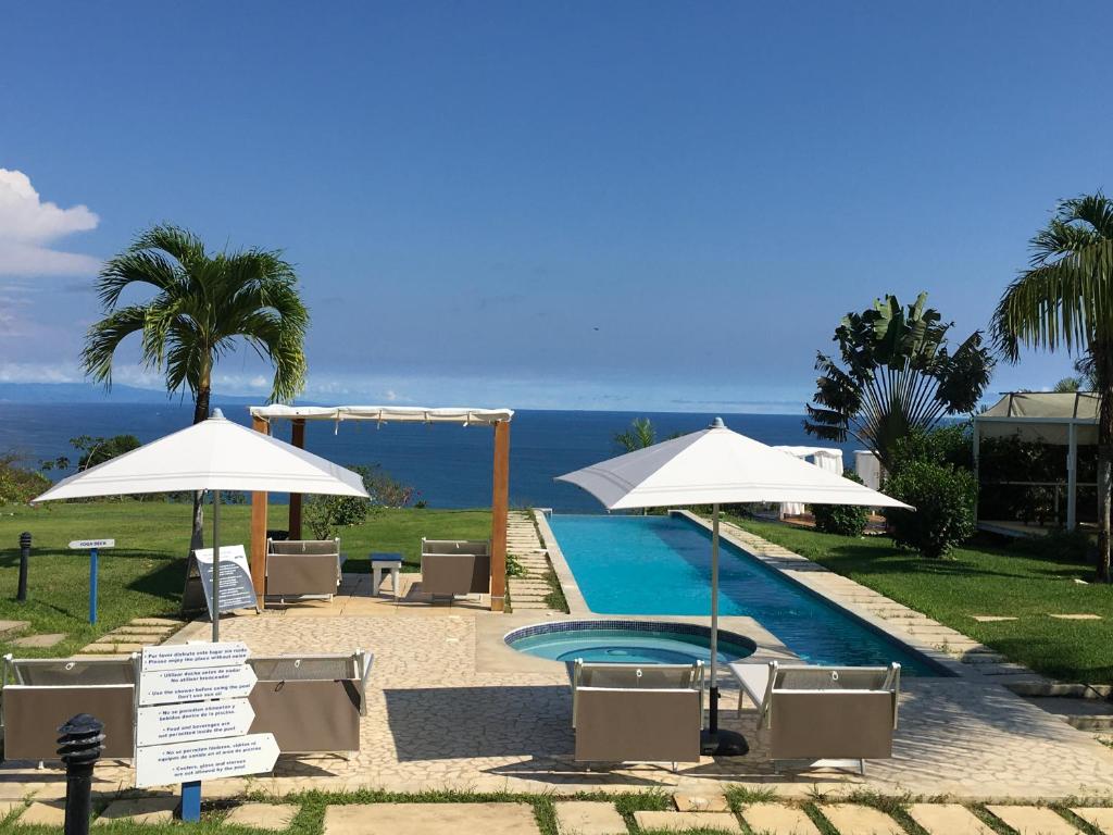 una piscina con sombrillas y sillas y el océano en Casitas Sollevante Boutique Hotel, en Montezuma