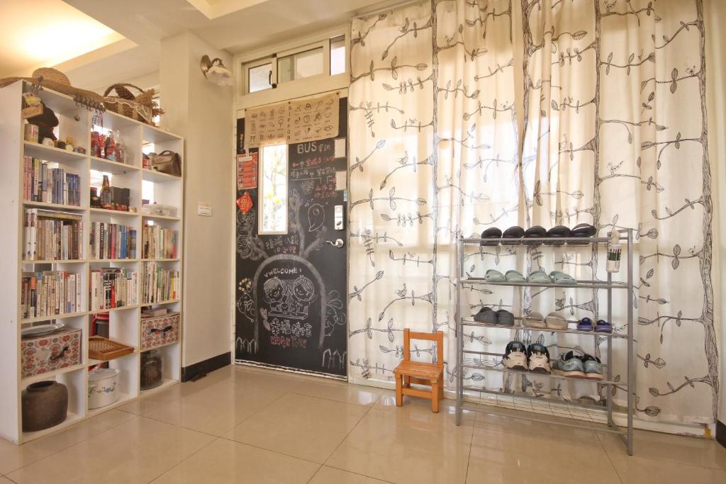 a room with a book store with a shelf of shoes at Happy Tree Hostel in Jinning