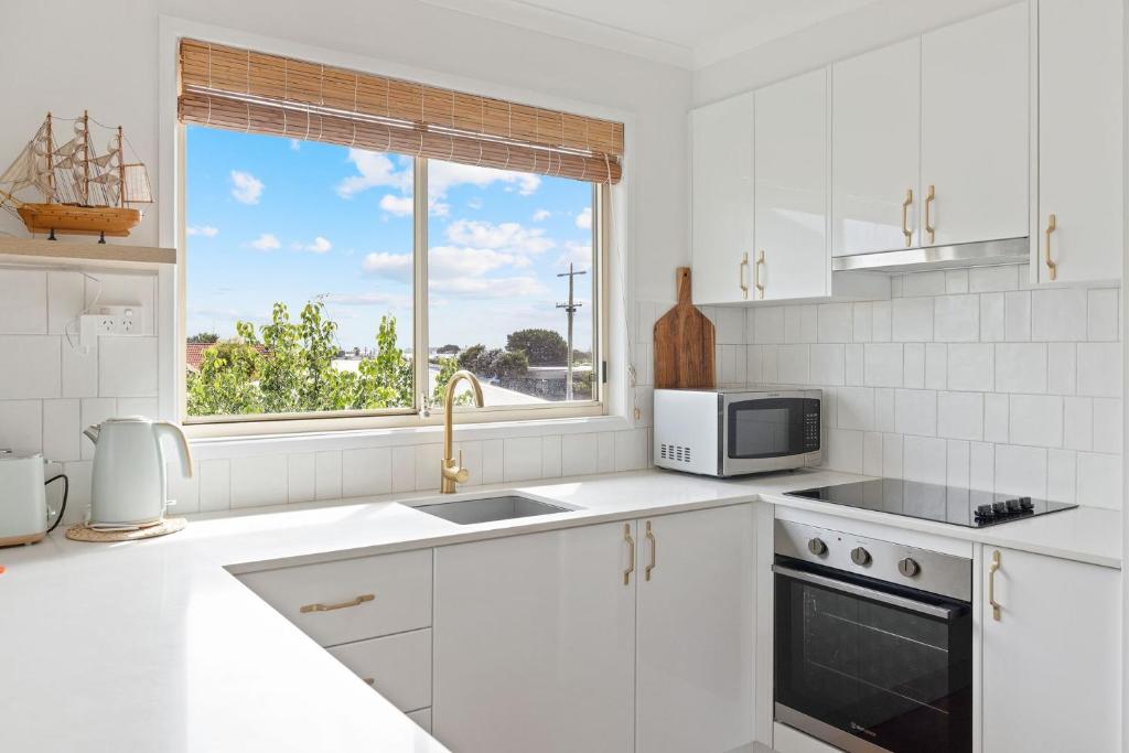 a white kitchen with a sink and a window at Lazy Daze at SummerHaze in Cape Woolamai
