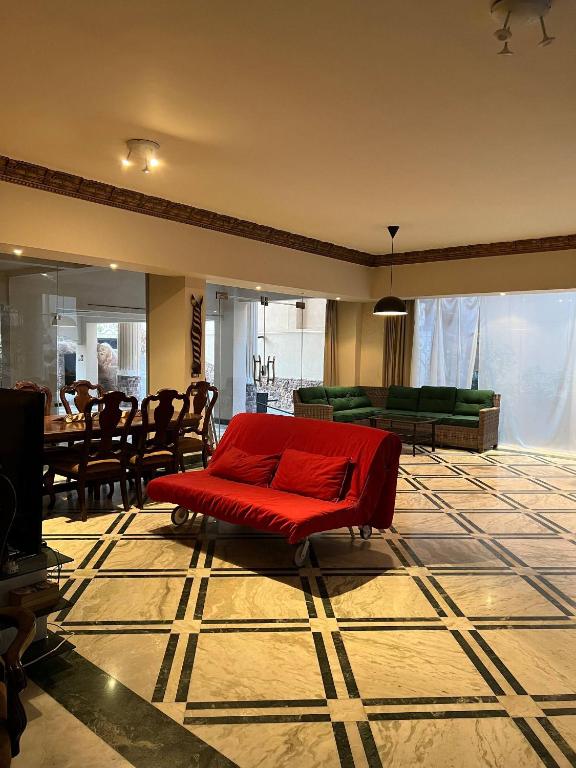 a living room with a red couch in the middle at The Glasshouse Pools in Cairo