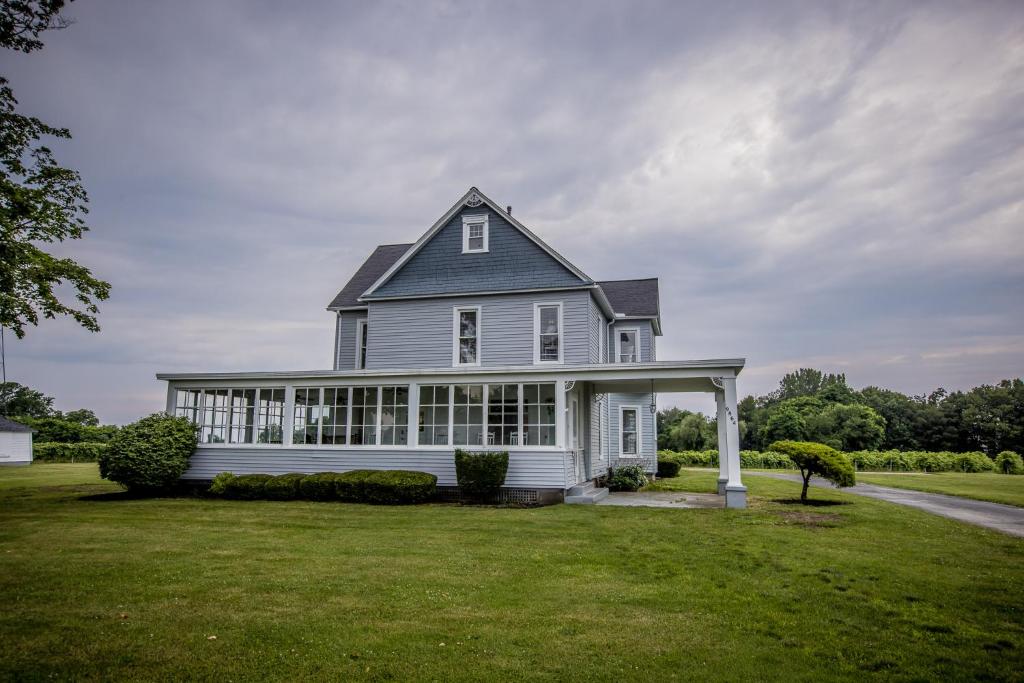 a white house with a gambrel roof at Lakeside Vineyard Farmhouse in North East