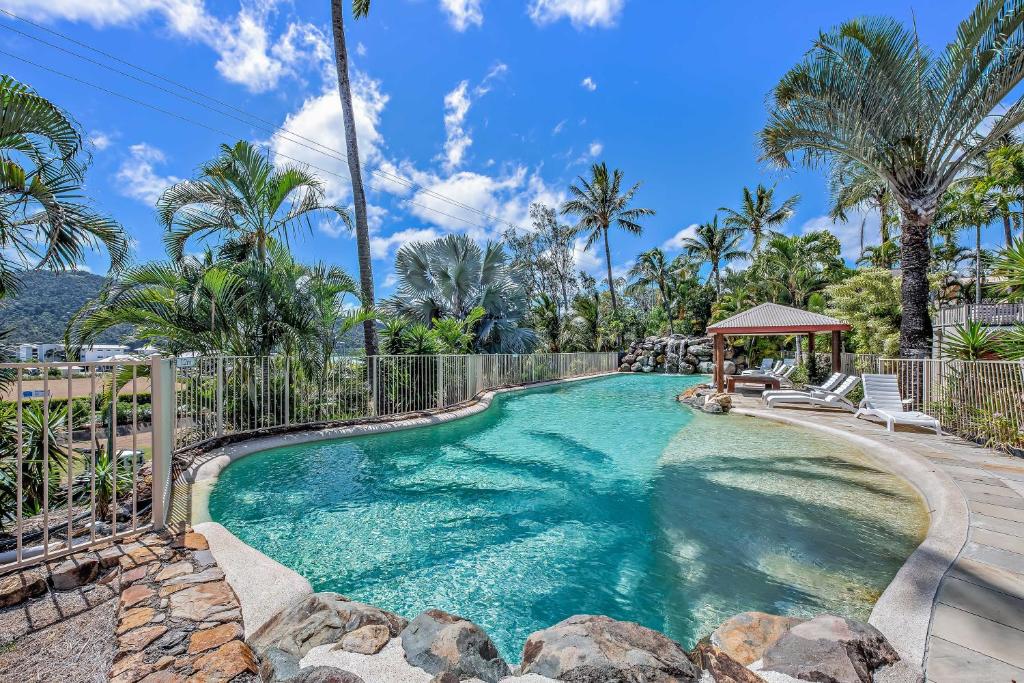 a swimming pool with a gazebo and palm trees at Spa Haven 17B Ocean View in Airlie Beach