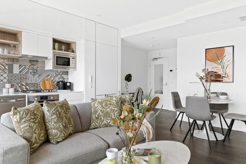 a living room and kitchen with a couch and a table at Modern Elegance Caulfield North in Melbourne