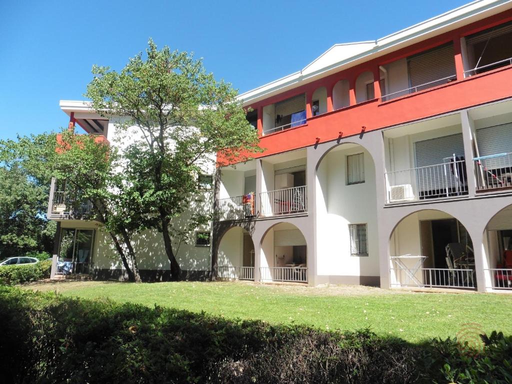 un grand bâtiment blanc avec un arbre devant dans l'établissement Charmant studio RDC avec terrasse, proche Thermes et centre-ville, accepte animaux - Lamalou-les-Bains - FR-1-451-98, à Lamalou-les-Bains