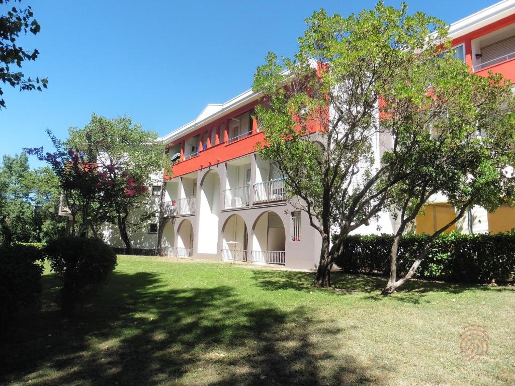 un bâtiment rouge et blanc avec des arbres devant lui dans l'établissement Charmant appartement avec terrasse, parking gratuit et animaux acceptés, proche des thermes à Lamalou - FR-1-451-89, à Lamalou-les-Bains