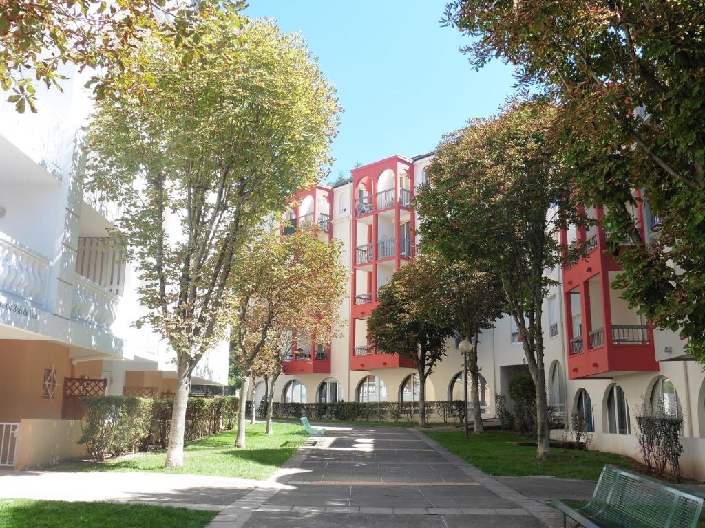 un bâtiment rouge et blanc avec des arbres devant lui dans l'établissement Studio Lamalou-les-Bains, 1 pièce, 2 personnes - FR-1-451-96, à Lamalou-les-Bains
