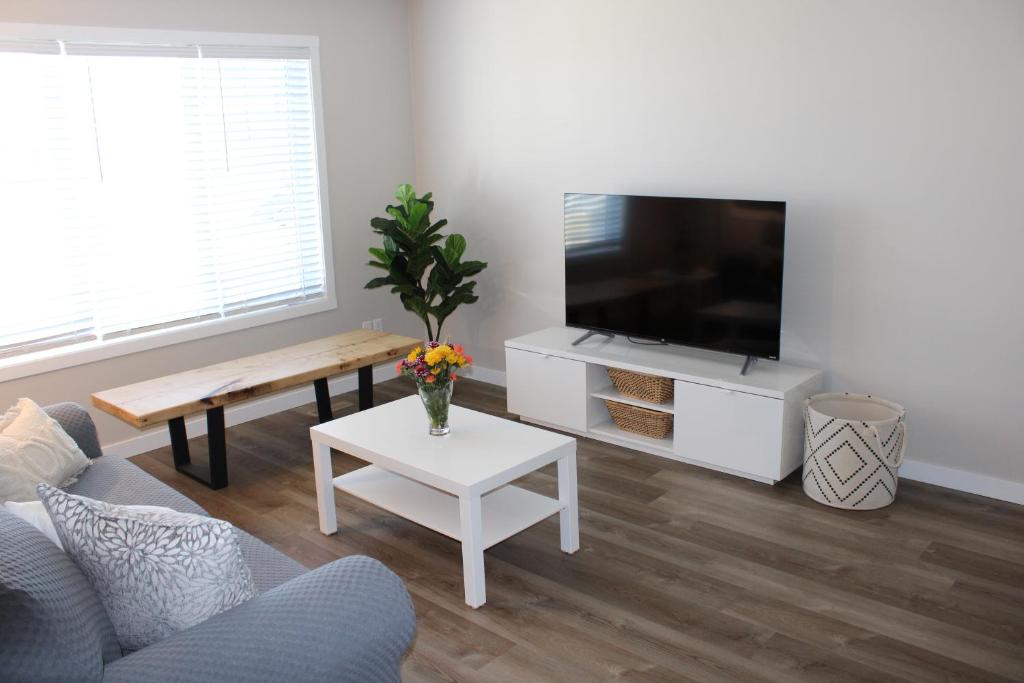 a living room with a tv and a couch and a table at Freshly Updated 3 Bedroom Townhome in Lethbridge