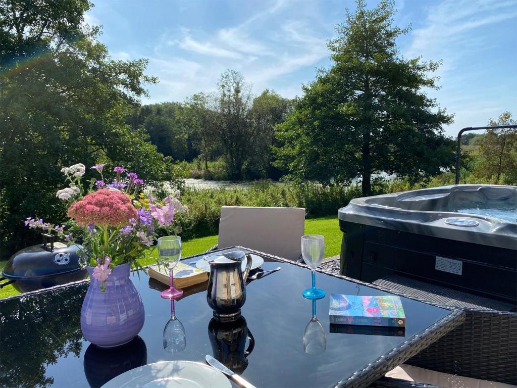 a table with a vase of flowers on a table with a hot tub at Robin Cottage in Llandeilo