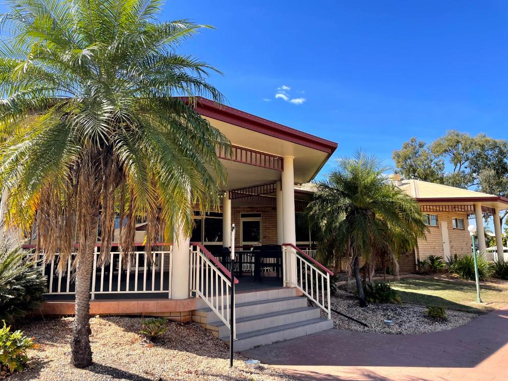 una casa con palmeras delante en Western Heritage Motor Inn, en Moranbah