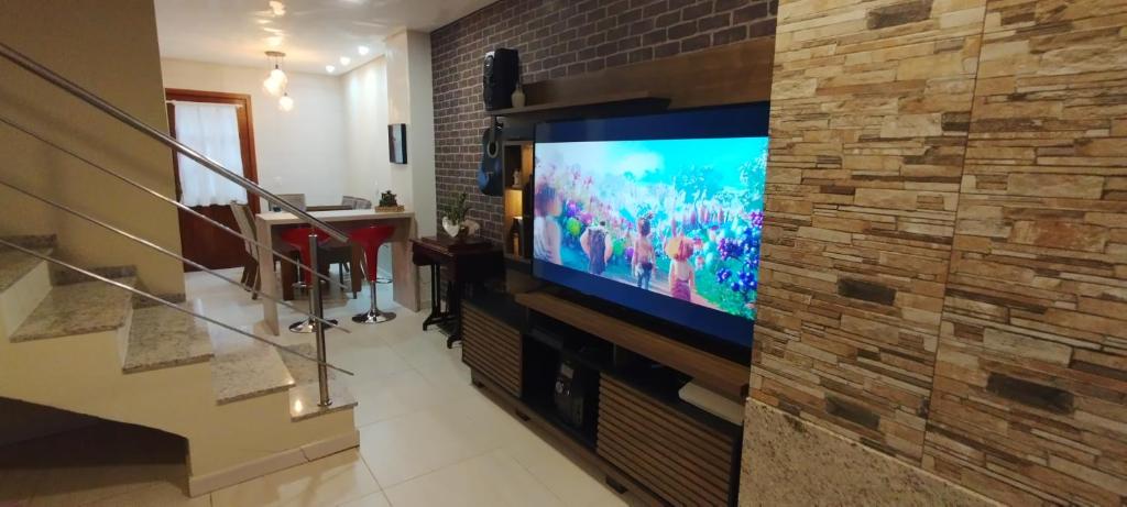 a living room with a tv and a brick wall at Casa Joaninha centro in Canela