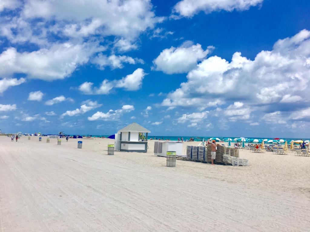 una playa con sillas y sombrillas y gente en ella en Ocean Walk by Miami Ambassadors, en Miami Beach