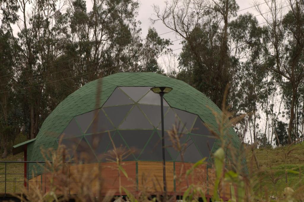 a green domed building with trees in the background at Glamping San Sebastian in Suesca