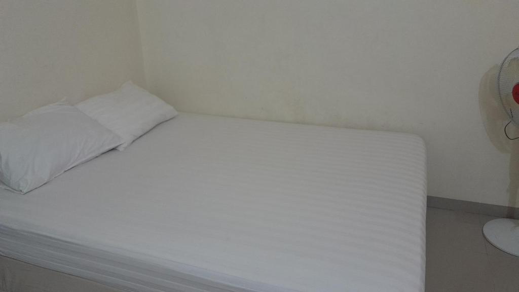 Cama blanca en una esquina de habitación en Hotel rejeki, en Lewoleba