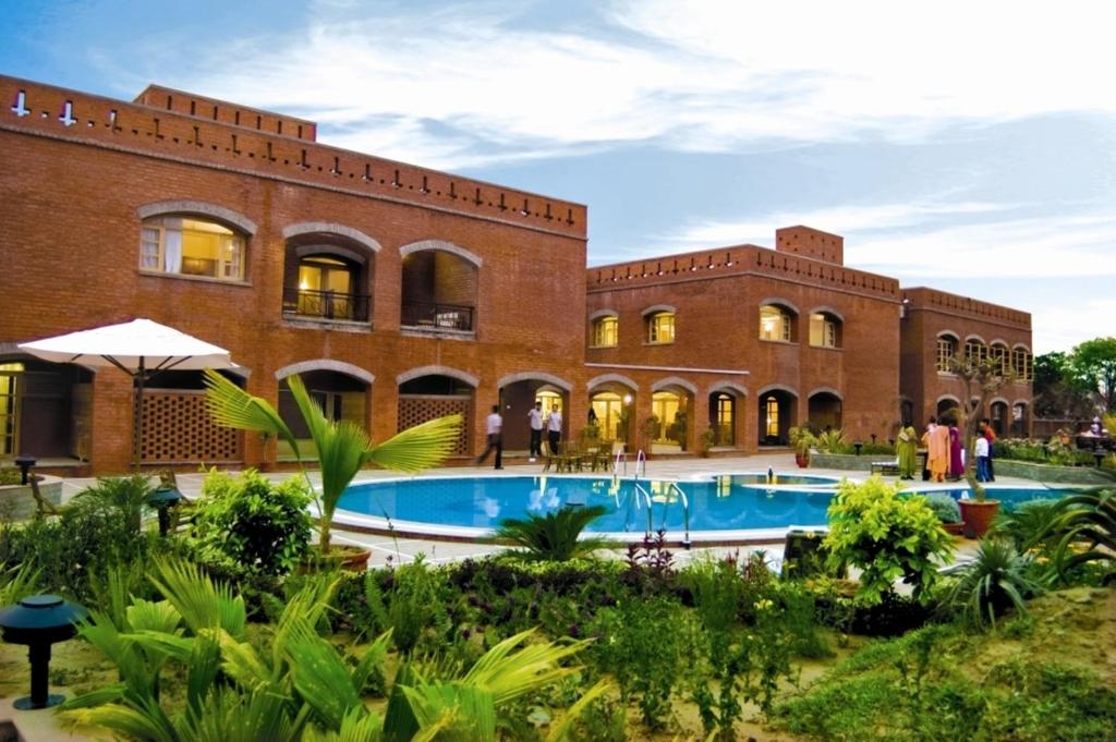 a resort with a swimming pool in front of a building at Cambay Sapphire, Gandhinagar in Gandhinagar