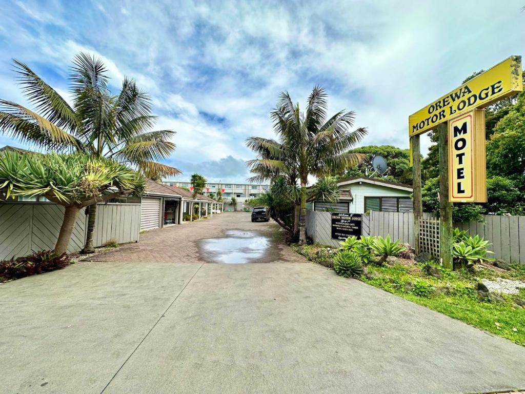 een straat met palmbomen en een bord voor een motel bij Orewa Motor Lodge in Orewa