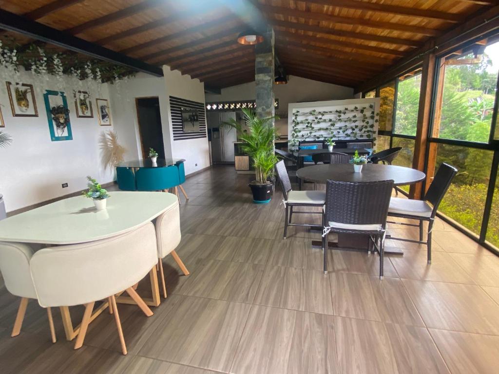 uma sala de jantar com mesas, cadeiras e janelas em Eros Hostel & Brunch em Guatapé