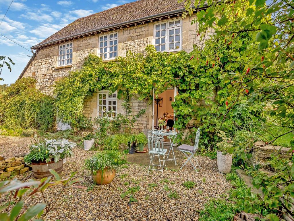 a stone house with a table and chairs in front of it at Fletchers Knapp in Bisley