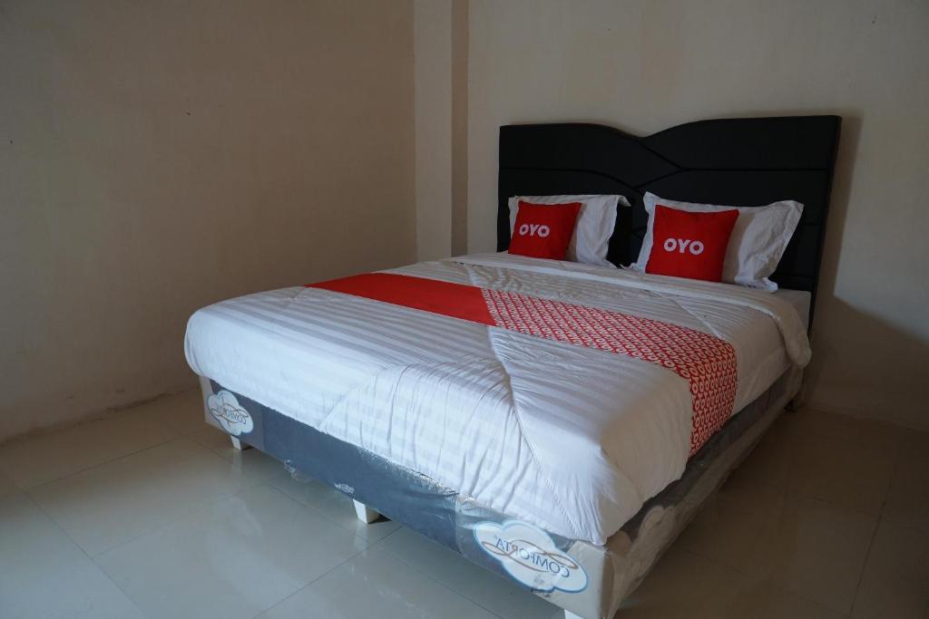 ein Schlafzimmer mit einem Bett mit zwei roten Kissen in der Unterkunft OYO 93205 Kusuma Hotel And Convention Hall in Nganjuk
