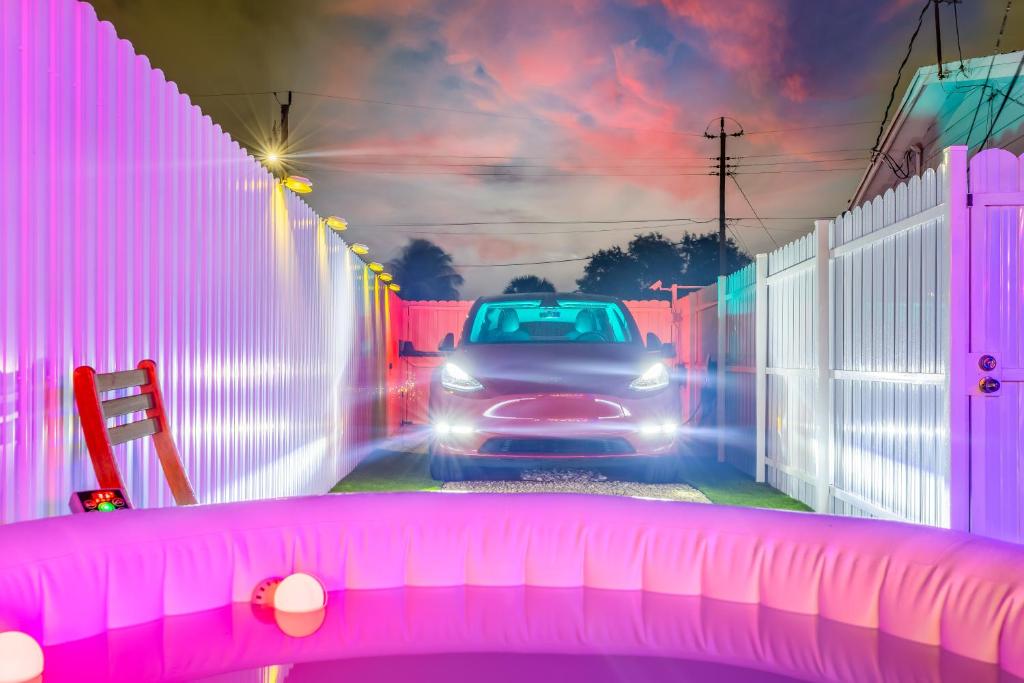ein Auto, das eine Straße mit einem rosa Zaun entlangfährt in der Unterkunft Smart Tiny House Garden in Miami Gardens