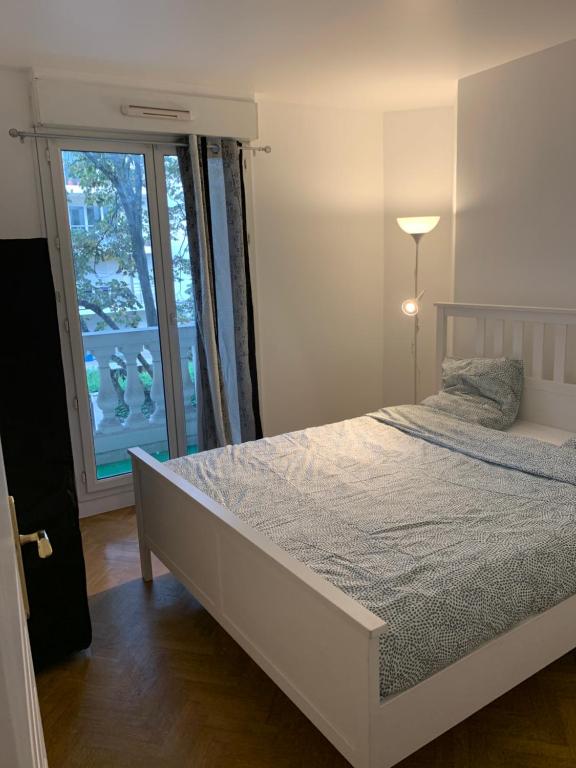 a bedroom with a bed and a large window at Lieu de ressourcement à Robinson in Le Plessis-Robinson
