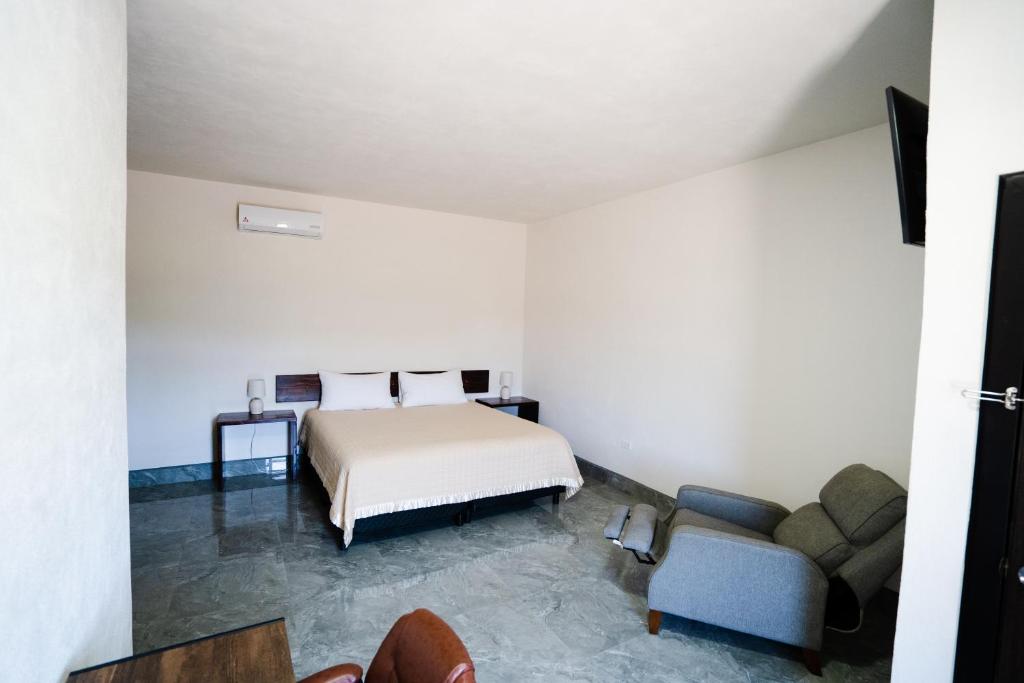 ein Schlafzimmer mit einem Bett, einem Sofa und einem Stuhl in der Unterkunft HOTEL & RV PARK ROSA EVELYN in San Quintín