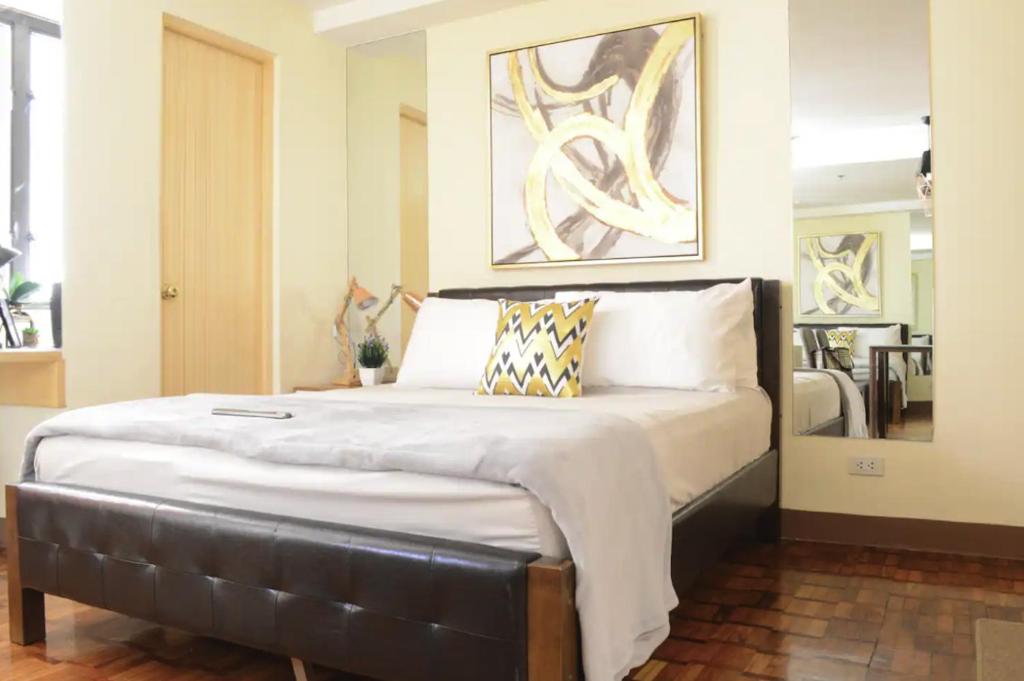 a bedroom with a large bed with a leather headboard at Studio Suite beside Greenbelt Mall Makati City in Manila