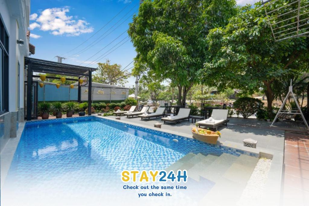 una piscina con sedie a sdraio accanto a una casa di Viet Long Hoian Beach Hotel - STAY 24H a Hoi An