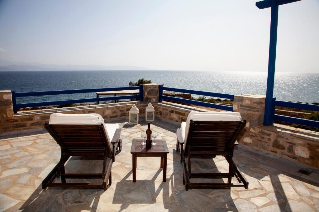 2 Stühle und ein Tisch auf einem Balkon mit Meerblick in der Unterkunft Aura Paros in Logaras